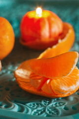 A burning candle in the shape of a tangerine. Holiday advent. Beautiful handmade candles.