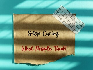 Torn stick note with handwritten text STOP CARING WHAT PEOPLE THINK, self reminder to stop the...