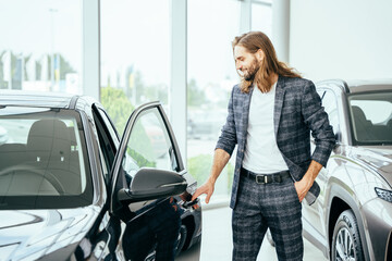 Fototapeta na wymiar Happy beard long haired male customer in vehicle showroom, male person buying transport, auto dealer business.
