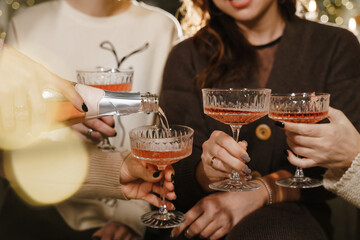 Hands of people celebrating New year party with wine drinking glasses and present background. New year eve and Christmas party concept. Happiness and Friendship together. Closeup