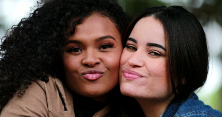 Two diverse women embrace and hug. Friends hugging outside at park