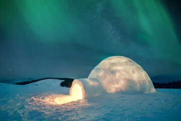 Aurora borealis. Northern lights in winter mountains. Wintry scene with glowing polar lights and snowy igloo. Landscape photography