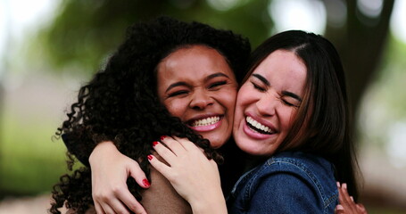 Two diverse women embrace and hug. Friends hugging outside at park