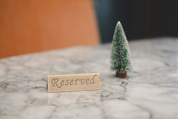 Reserved sign made out stainless steel plate on a table in a restaurant with Christmas tree at...