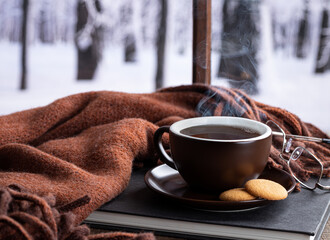 Steaming hot cup of coffee or tea by a window