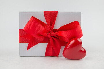  gift box with a red ribbon and a red heart on a white background.