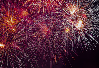 Abstract background - bright beams of festive colorful fireworks against black night sky.