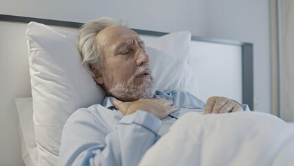 Senior gray-haired man holding hand on chest, feeling pain in lungs, risk of inflammation