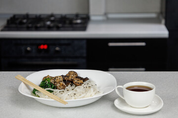 Plate with rice noodles and shiitake mushrooms. White mug with coffee