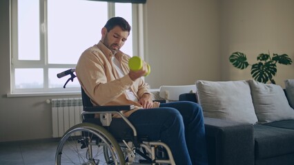 Man with disability doing dumbbell exercise while sitting in wheelchair, rehabilitation