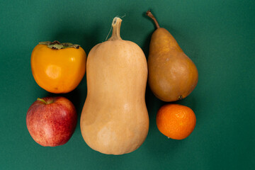 Pumpkin, apple, pear, tangerine and persimmon on a green background - Powered by Adobe