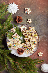 Christmas tree shape gingerbread cookies covered with white and dark chocolate, decorated with chopped pistachio nuts. Delicious homemade New Year sweet baking. 