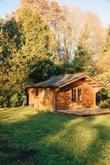 Small wooden house in a beautiful garden with lots of sun. Garden in summer or spring. Wooden garden shed. Secluded little cottage in the woods