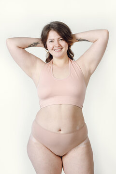 A smiling woman of large sizes in underwear. A plump girl on a light background, a positive attitude to the body.