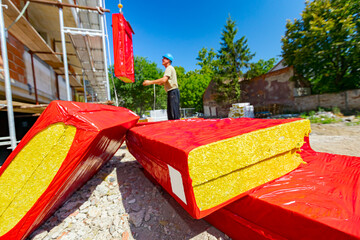 Packages with stone wool arranged in a pile, the workman is hanging the packet with stone wool on...
