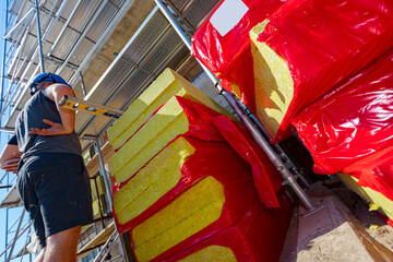 Stacks of thermal insulation material packed in cellophane foil, manager controls work
