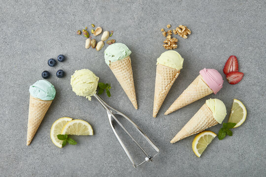 Row of waffle cones with assorted gelato arranged on gray table