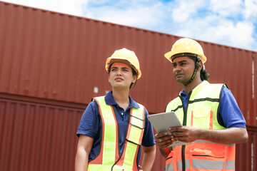 Professional indian male and female workers in hard hat safety clothes. Talk to load the product into the container at the warehouse.