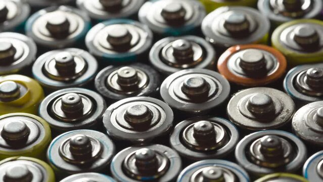Preparing Batteries for Disposal. Dense AA battery array moves with slight rotation close-up with backlight