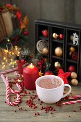 Cocoa cup, Christmas sweets, candle and decorations on wooden table, blurred background. Christmas...