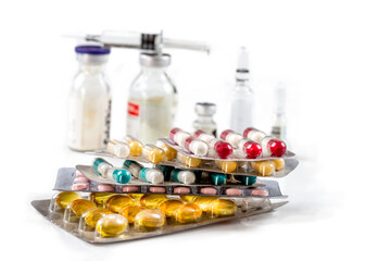 Pharmacology and medicine concept. Assorted pharmaceutical medicine pills, tablets, and capsules Liquid from glass vial and syringe . On a white background.