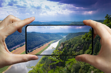 Tourist taking a picture with a mobile phone of the river Elbe at the sandstone mountains in Saxony, Germany. - obrazy, fototapety, plakaty