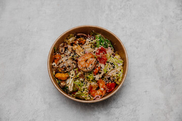 Seafood salad in a craft plate on a gray background. View from above.
