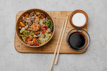 Seafood salad in a craft plate and a bowl with soy sauce on a gray background.