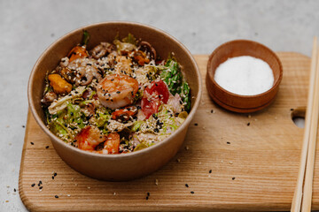 Seafood salad in a craft plate on a gray and wooden background.