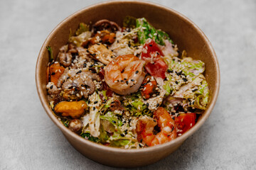 Seafood salad in a craft plate on a gray background. Side view.
