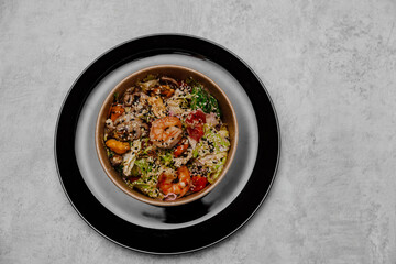 Seafood salad in a craft plate on a gray background. View from above.
