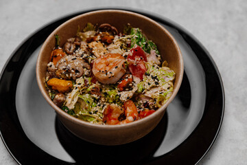 Seafood salad in a craft plate on a gray background. Side view.
