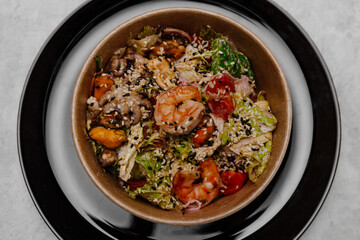 Seafood salad in a craft plate on a gray background. View from above.
