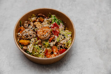 Seafood salad in a craft plate on a gray background. Side view.
