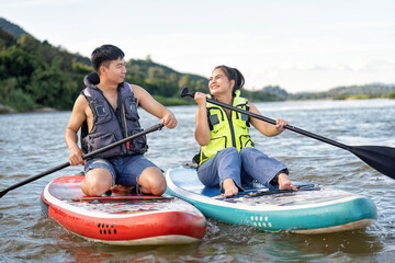 On summer holiday love couple relax sail sup board surf on river on beautiful nature calm river