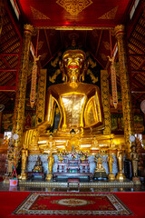 Obraz premium Goldener glänzender überdimensionaler sitzender Buddha welcher in einem thailändischen Tempel ist, in Chiang Rai, Nordthailand, Asien