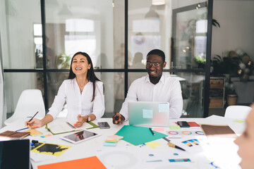 Cheerful multiethnic coworkers laughing during conference