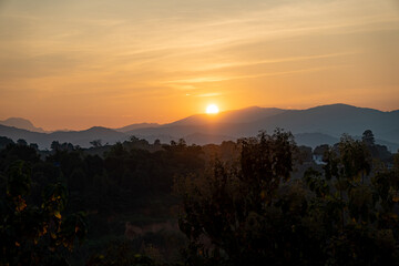 orangener goldener Sonnenuntergang in Chiang Rai, Norden von Thailand mit Bergen im Hintergrund,...