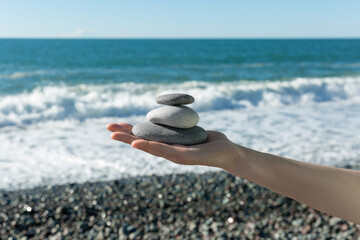 Balance of stones on the hand against the background of the sea. The concept of peace of mind,...
