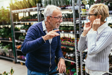 Senior couple are choosing potted plant at garden center.