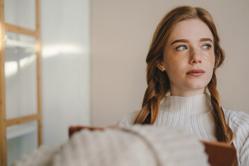 Naklejka premium Woman sitting on sofa covered with a blanket writing in notebook. A cozy way of life .