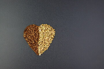 The green and brown buckwheat are laid out in the shape of a heart. Two kinds of buckwheat on a gray background. 