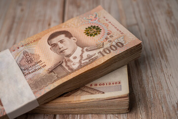 Stack of Thai baht banknotes on wooden background, business saving finance investment concept.