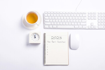 Conceptual,mouse and keyboard with clock and tea on white blackground work space.open diary with new year's resolutions 2023.