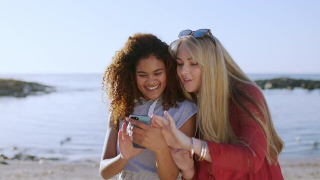 Friends, gossip news or laugh with phone, social media post and funny internet meme at beach. Happy, smile and crazy girls watch mobile comedy streaming with tech, online app and web connect at ocean