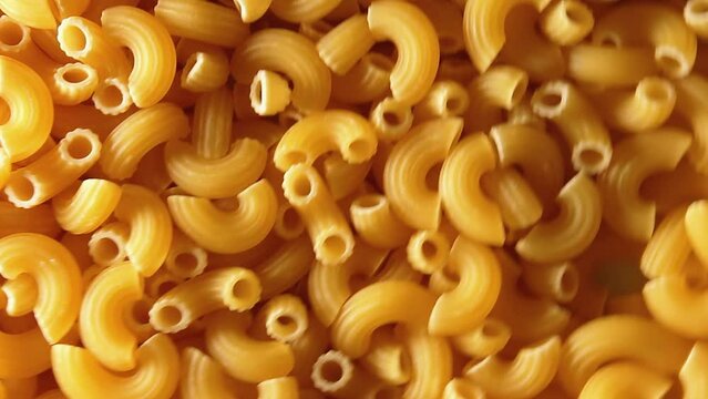 Uncooked Chifferi Rigati Pasta - Top View, Low Key. Fat and Unhealthy Food. Classic Dry Macaroni, Rotating Background. Italian Culture and Cuisine. Raw Golden Pasta Texture - Right Angular Rotation