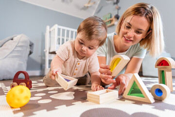 Loving family mom and baby boy playing together toys on floor in child room