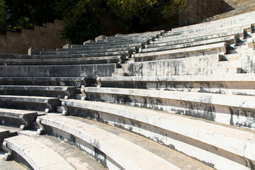 Fototapeta na wymiar Odeon a classic greek open-air theatre. Old theater with marble seats and stairs. The Acropolis of Rhodes. Monte Smith Hill, Rhodes island, Greece