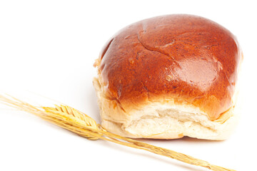 fresh baked wheat bun with wheat ears isolated on white.