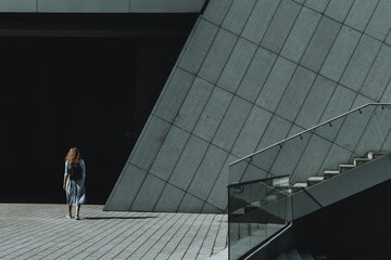 Woman steps into the shadow of the modern grey building
